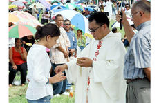 Marissa Laracuente, 11, receives Holy Communion from Father Carl Vila during the All Souls Day Mass on Wednesday in the Guam Veterans Cemetery.