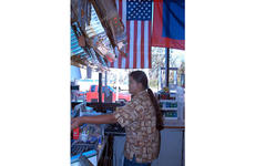 A cashier at a gas station in southern Guam waits on customers, while the Guam and U.S. flags hang in the window.