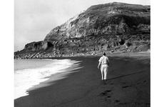 Air Force Capt. John S. Gunnison, who took part in the World War II invasion of Iwo Jima as a Marine 15 years earlier, walks along the beach toward Mt. Suribachi during his first visit to the island since the battle.