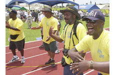 Volunteer encouragers, from right to left, Marine Staff Sgt. Kelvin Roberts, Earl Gittens, Gunnery Sgt. Darryl Dyson and Gunnery Sgt Terrell Lasker cheer on runners in a 100-meter dash.
