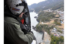 Petty Officer 2nd Class James Rivers looks out the side of a Seahawk helicopter at the tsunami damage along the coastline of northeastern Japan during a humanitarian relief supply mission in Iwate Prefecture.