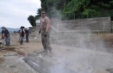 Petty Officer 1st Class Joshua Thonnissen tosses a powder meant to help kill bacteria into a drainage ditch in Miyako, Japan, on Thursday.