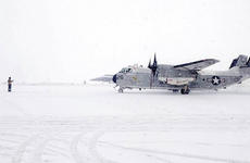A sailor from Naval Air Facility Misawa - on Misawa Air Base, Japan - guides a C-2 passenger plane onto the ramp to disembark personnel during a heavy snow storm Saturday mor