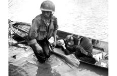 A little girl, hit in the shoulder by a slug from an aircraft machine gun, is tended to by a medic before being evacuated to a hospital by South Vietnamese troops.