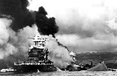The USS Maryland floats beside the capsized USS Oklahoma, Dec. 7, 1941, as the USS West Virginia burns in the background following Japan's surprise attack on Pearl Harbor, Hawaii.