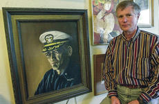 In a February, 2000 photo, Robert J. Chicca stands next to a portrait of his former Commander, Lloyd "Pete" Bucher, that he painted himself.