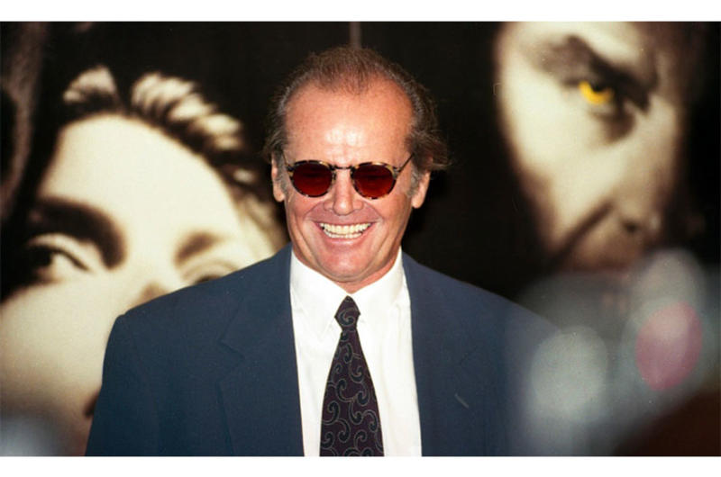 Actor Jack Nicholson, sporting his trademark shades and leer, poses in front of a poster of himself and "Wolf" co-star Michelle Pfeiffer during a press conference at Tokyo's Imperial Hotel in 1994.