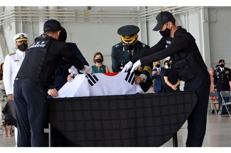 South Korean officials cloak their national flag over a box holding the remains of a countrymen who died during the Korean War during a repatriation ceremony at Joint Base Pearl Harbor-Hickam, Hawaii, Tuesday, June 23, 2020.