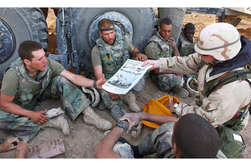 In a 2003 photo, Command Sgt. Maj. John Sparks delivers copies of Stars and Stripes to U.S. Marines from Weapons Platoon, 3-2 India Company.