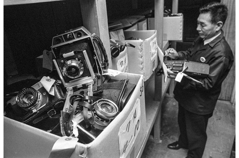 Tsutome Sekine and some of the expensive items, including a large Speed Graphic-type camera, in storage at the Tokyo Lost and Found office in December, 1975.