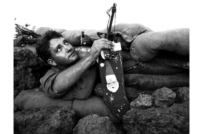 Pfc. Orville Painter, 22, of Modesto, Calif., leans out of his bunker at Ka Tum, 50 miles northwest of Saigon, to hang his Christmas stocking.