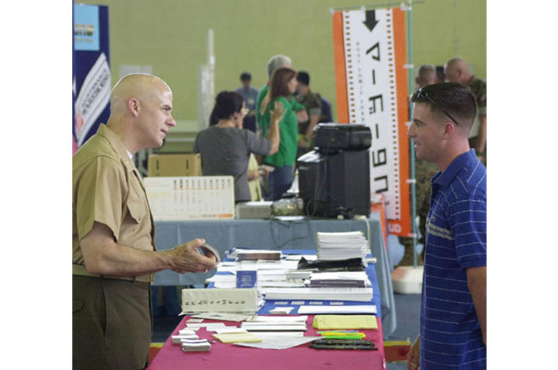 Marine Maj. Phillip Woody performs magic card tricks to draw customers to the Defense Logistics Agency booth during the Camp Foster Vendor Fair Thursday.