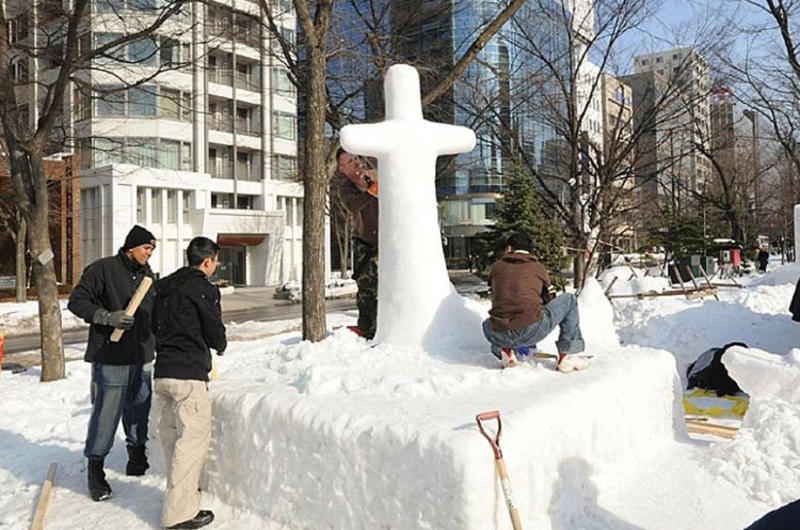 U.S. sailors and members of the Japan Ground Self-Defense Force work Friday to rebuild a snow sculpture that collapsed in unseasonably warm weather on Thursday at the Sapporo Snow Festival.