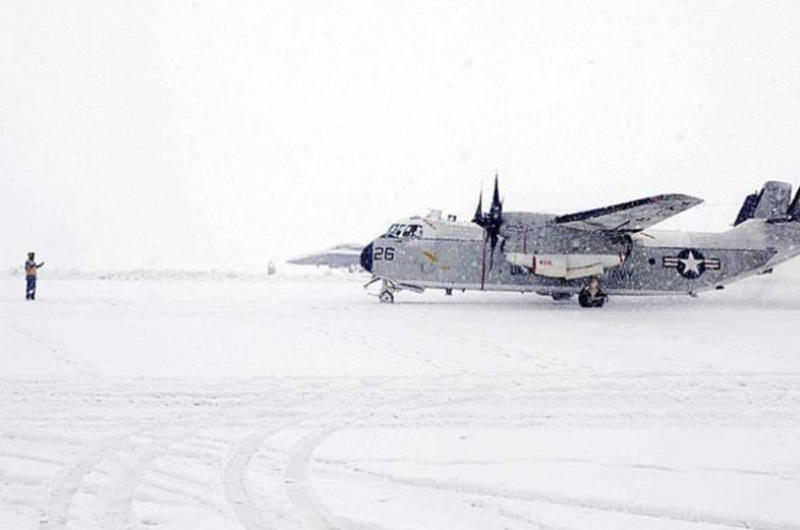 A sailor from Naval Air Facility Misawa - on Misawa Air Base, Japan - guides a C-2 passenger plane onto the ramp to disembark personnel during a heavy snow storm Saturday mor