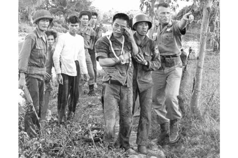 Maj. Robert M. Campbell, right, an American adviser from Fayetteville, N.C., points the way to a helicopter that will bring a wounded Vietnamese ranger, at center, to a hospital.