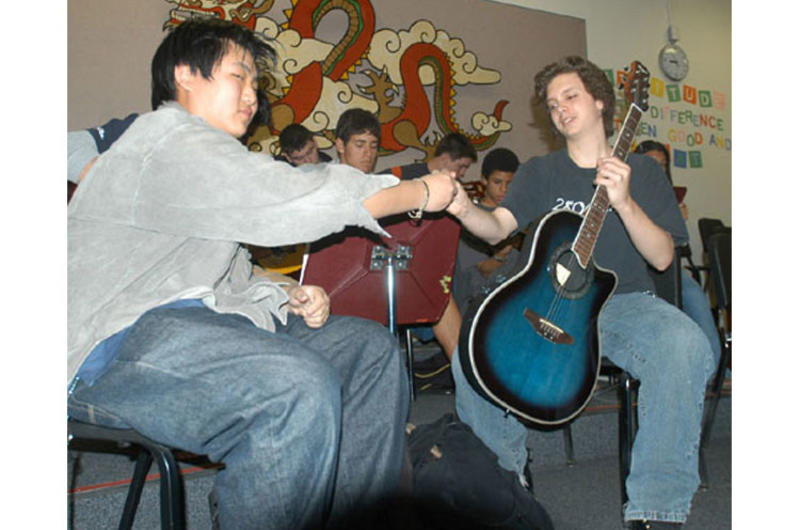 Kang Han-sul, left, a student at the German foreign school in Seoul, hands L.J. Christie a guitar in teacher Lisa Riehle's guitar class.