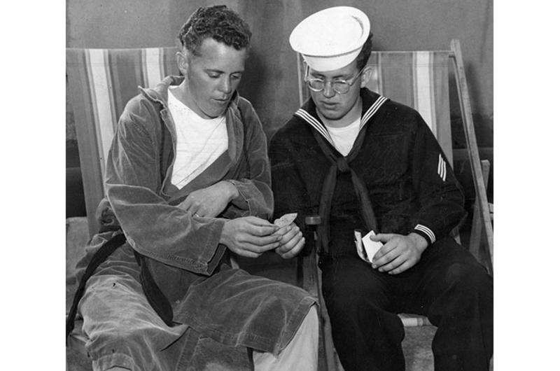 Cpl. William L. Conley, 23, Morrilton, Ark., recently released from a Communist prisoner of war camp, and brother, SM Tom, 20, of the destroyer Laws, look at Tom's pictures and clippings from home during their visit on the 8167th Army Hospital sundeck.