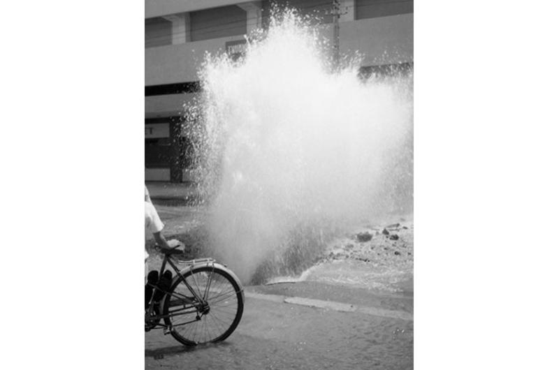 Water shoots out of a burst pipe under a road in Saigon.