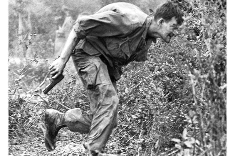 A U.S. 1st Cavalry soldier makes a dash for cover as North Vietnamese troops fire on his unit near a battered personnel carrier in the area around Chu Lai.