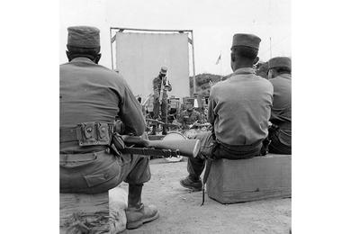 Rifle-carrying Yanks of the 34th Inf. Regt. listen to an open air concert by the 24th Div. Band.