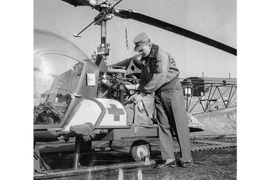BLOMQUIST CHECKS PATIENT BEFORE FLIGHT. 1st Lt. Paul Blomquist secures a patient to the outside of his Bell H-13 Sioux helicopter.