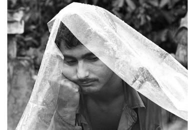 Spec. 4 Nicholas Rossi of Westmont, N.J., waits out a rainstorm beneath a plastic cover at the 2/27th, 25th Infantry Division command post northwest of Cu Chi, in South Vietnam's Iron Triangle.